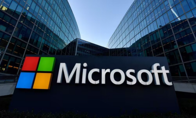 Microsoft's iconic logo sign stands prominently in front of its modern glass office buildings, symbolising innovation and global leadership in technology.